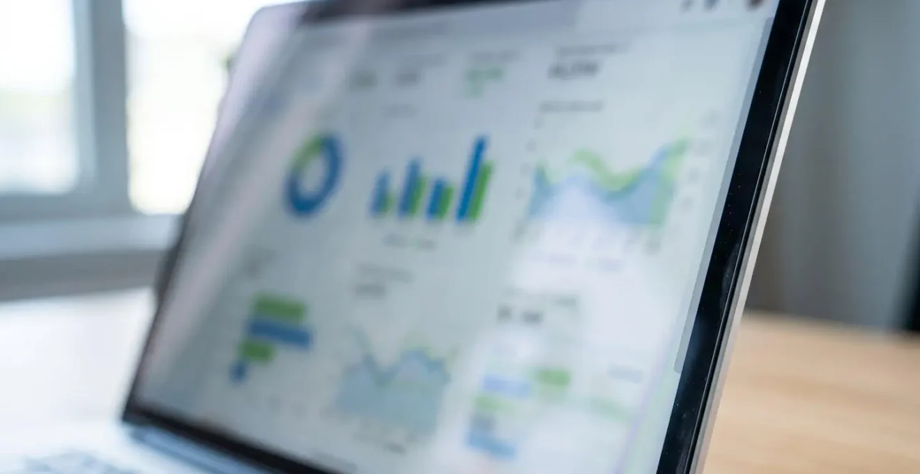 Gros plan sur un écran d'ordinateur portable affichant des graphiques de données et tableaux statistiques, mise au point sur les chiffres, contenu écran flouté